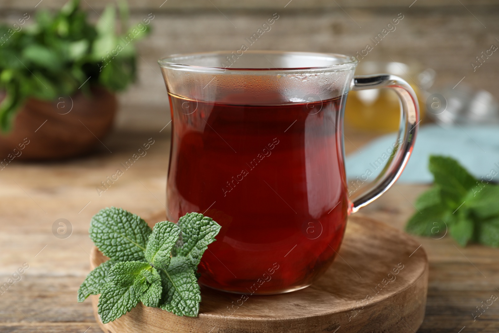 Photo of Cup of hot aromatic tea with mint on wooden table, closeup