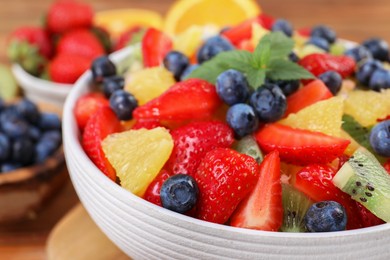 Delicious fresh fruit salad in bowl on table, closeup