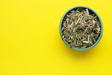 Bowl with aromatic dried lemongrass on yellow background, top view. Space for text