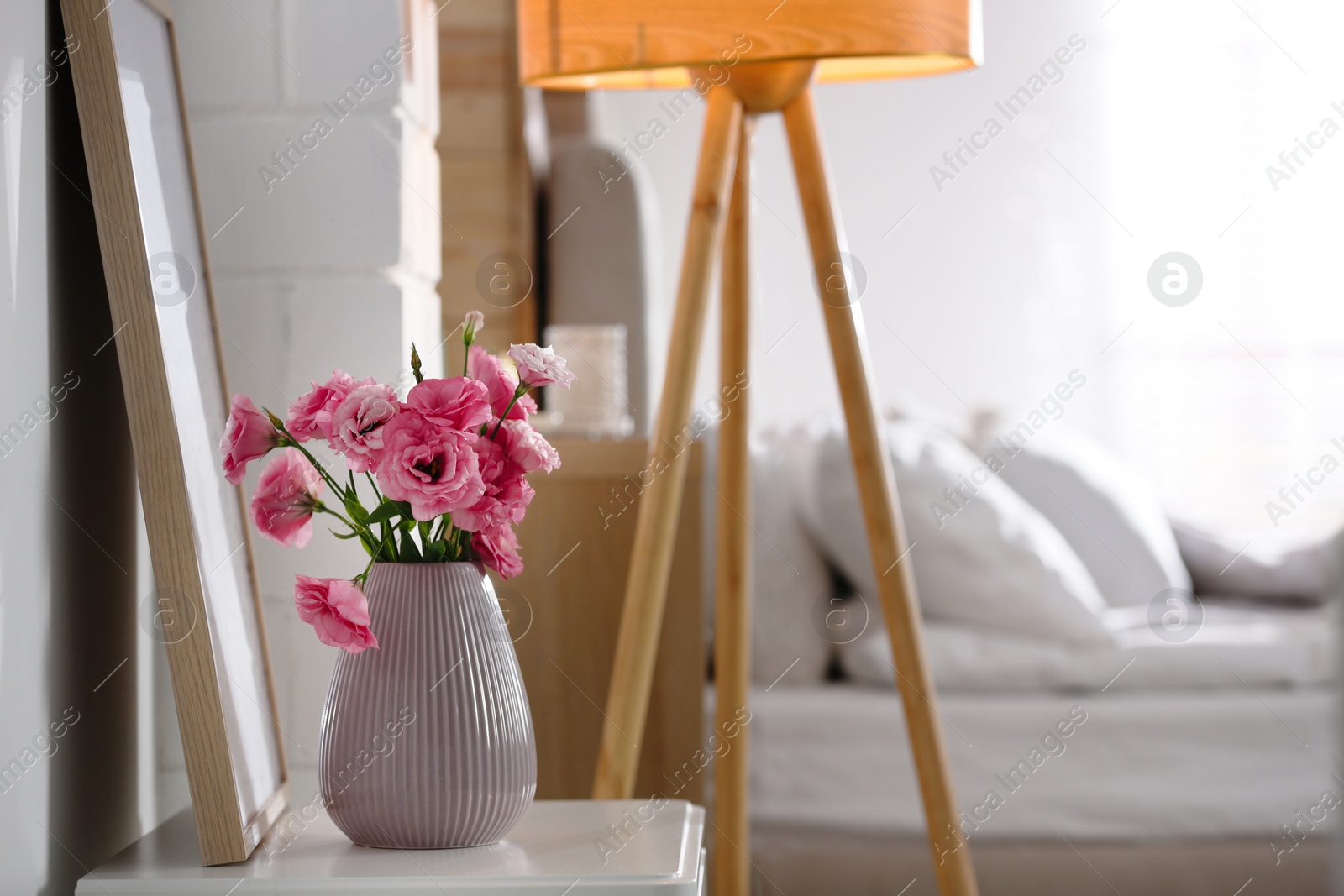 Photo of Vase with beautiful eustoma flowers on table in modern room interior, space for text