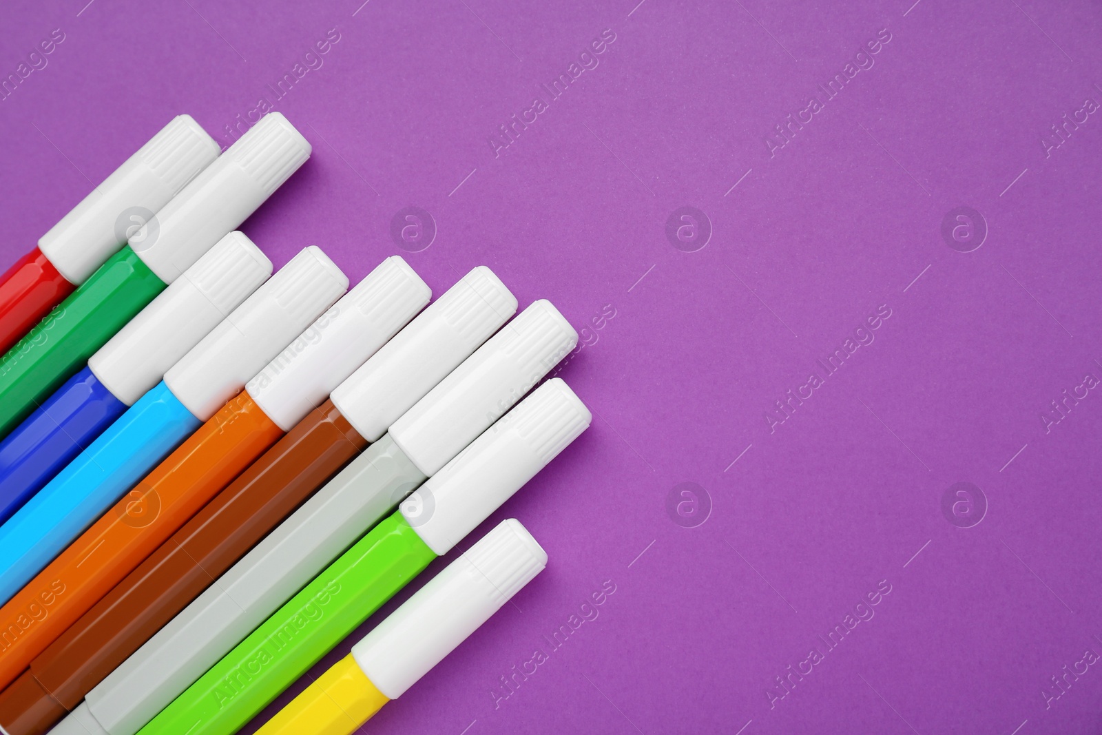 Photo of Different colorful markers on purple background, flat lay. Space for text