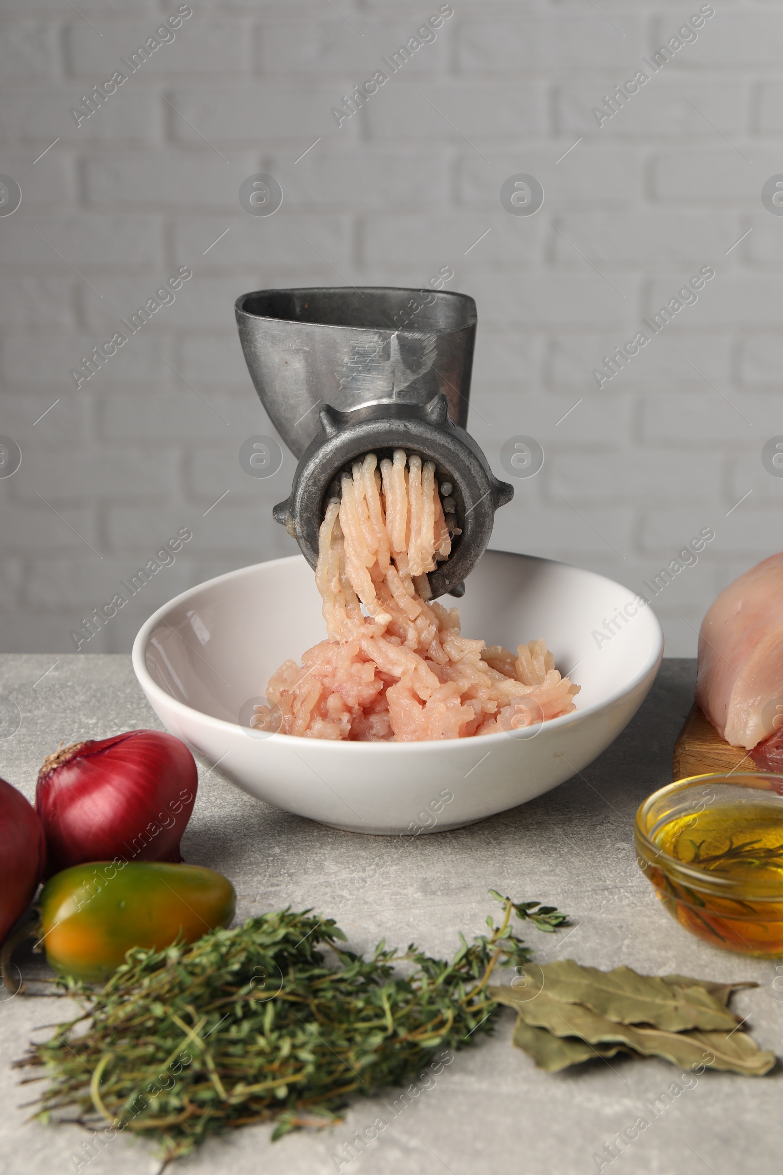 Photo of Metal meat grinder with chicken mince and different products on light grey table