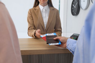 Man giving passports with tickets to agent at check-in desk in airport, closeup