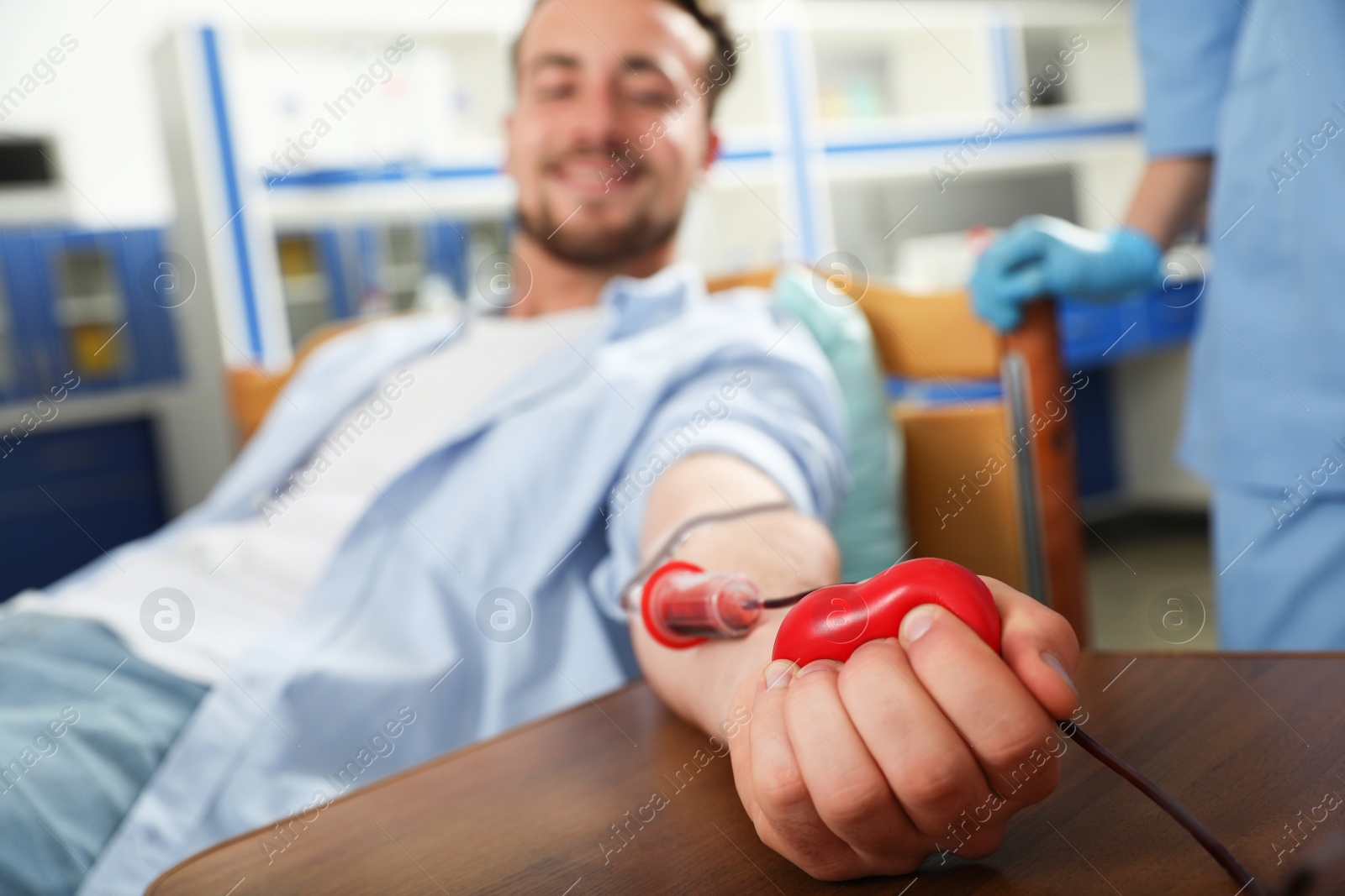 Photo of Young man making blood donation in hospital, focus on hand