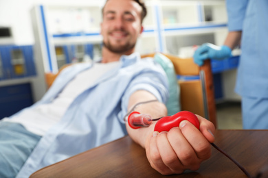 Photo of Young man making blood donation in hospital, focus on hand