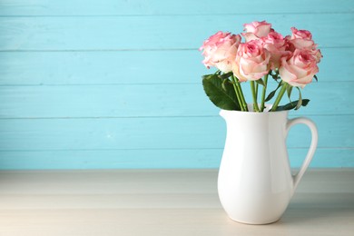 Photo of Vase with beautiful pink roses on wooden table. Space for text