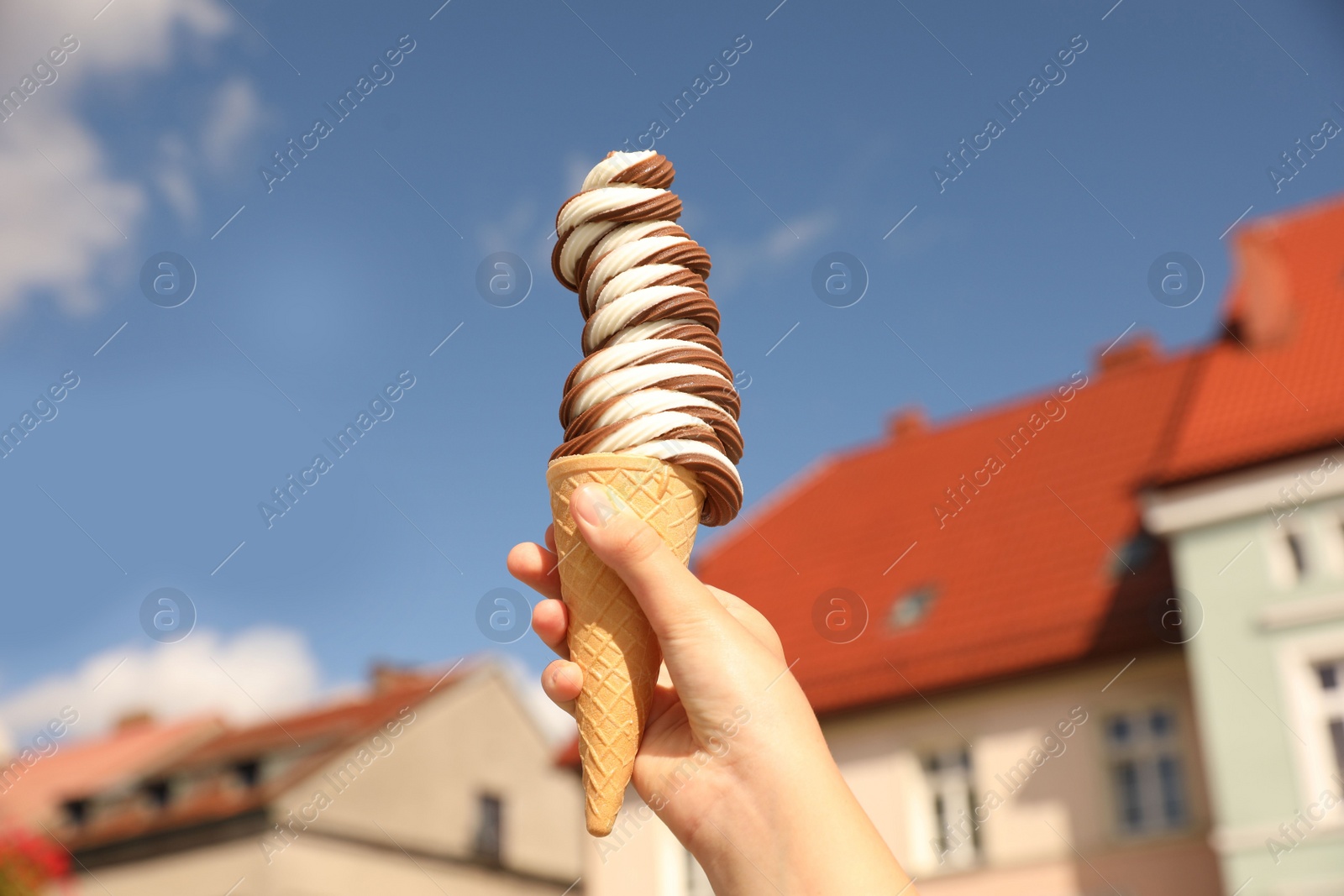 Photo of Woman holding delicious ice cream cone in city, closeup