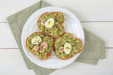 Photo of Slices of bread with tasty guacamole, eggs and shrimp on white wooden table, top view