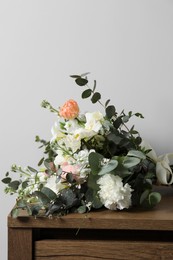 Photo of Bouquet of beautiful flowers on wooden table against white wall