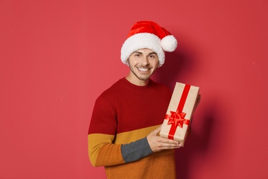 Photo of Young man with Christmas gift on color background