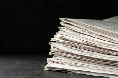 Stack of newspapers on dark stone table, space for text. Journalist's work