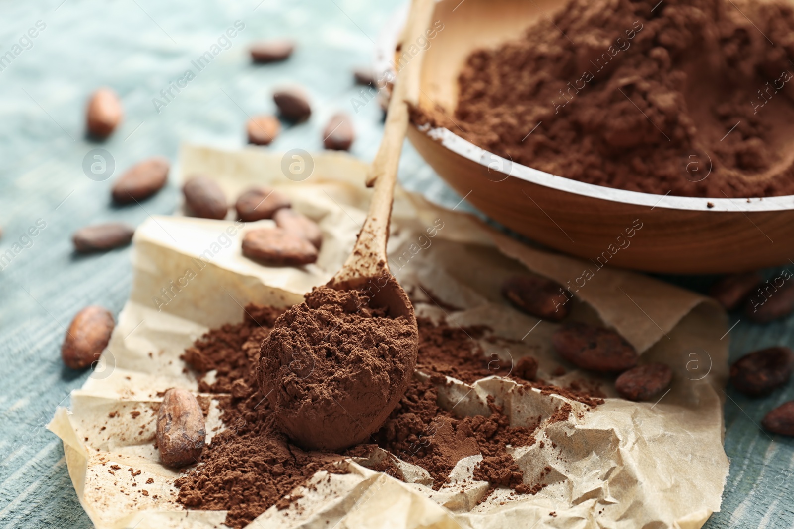 Photo of Spoon and plate with cocoa powder on table