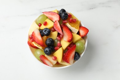 Photo of Tasty fruit salad in bowl on white table, top view