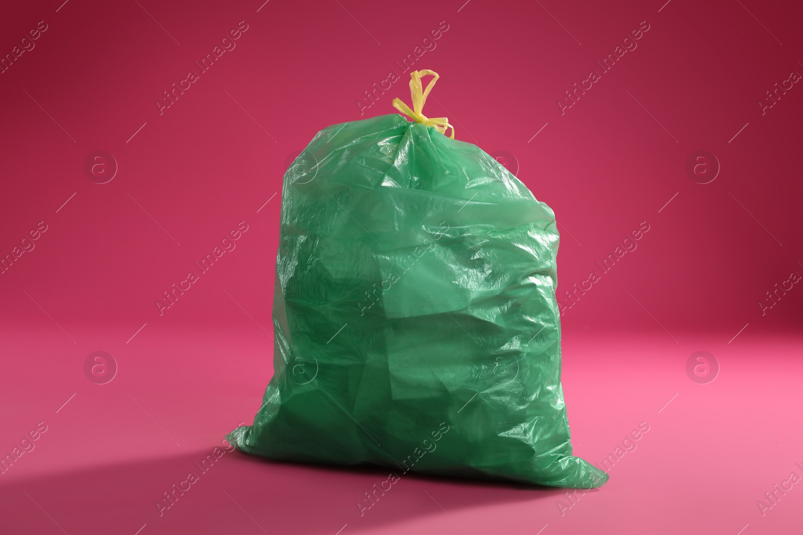 Photo of Trash bag full of garbage on pink background