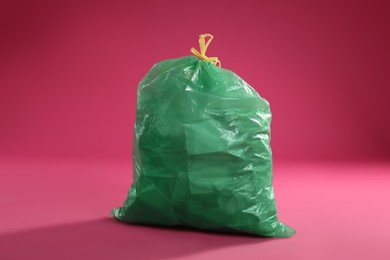 Trash bag full of garbage on pink background