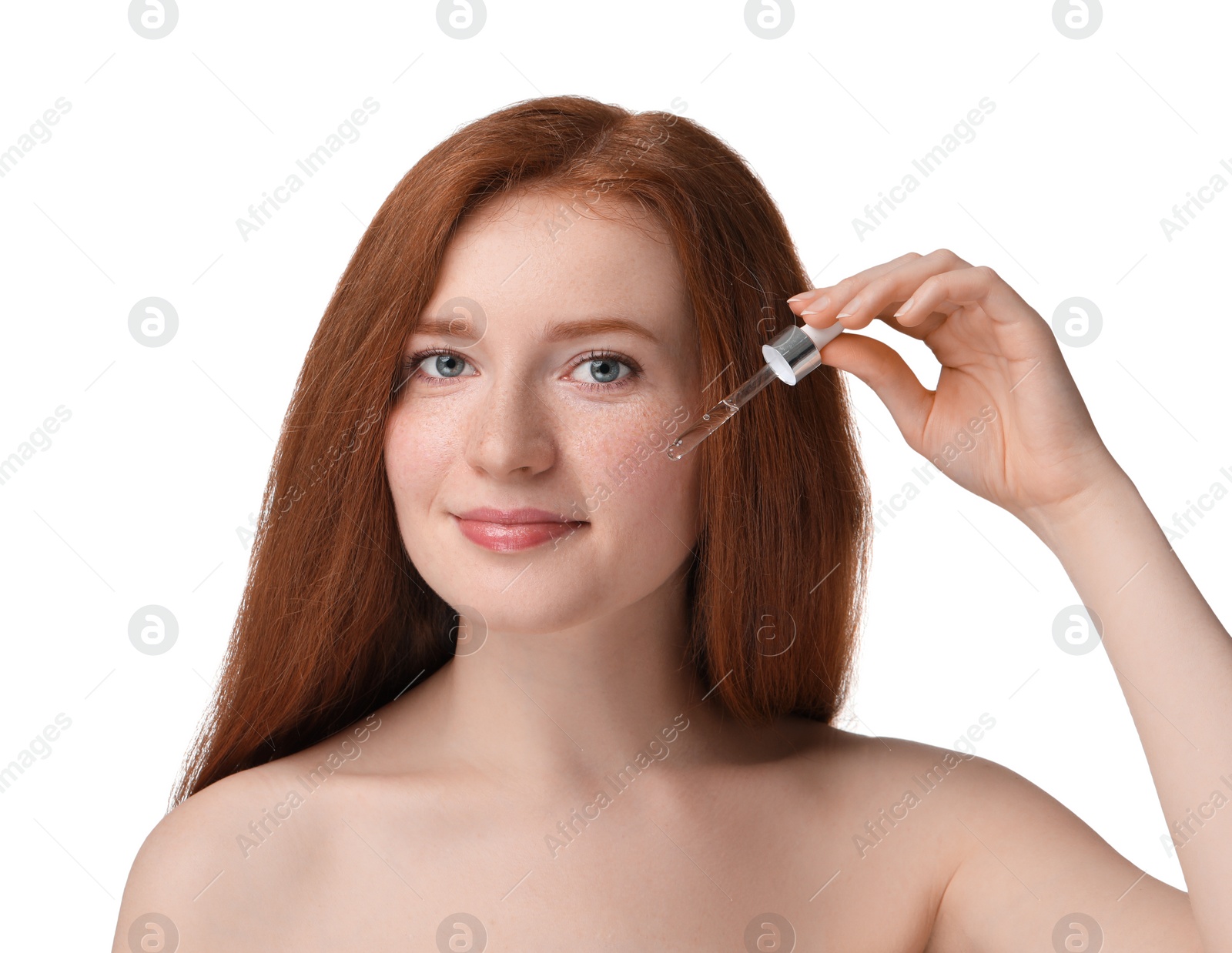 Photo of Beautiful woman with freckles applying cosmetic serum onto her face against white background