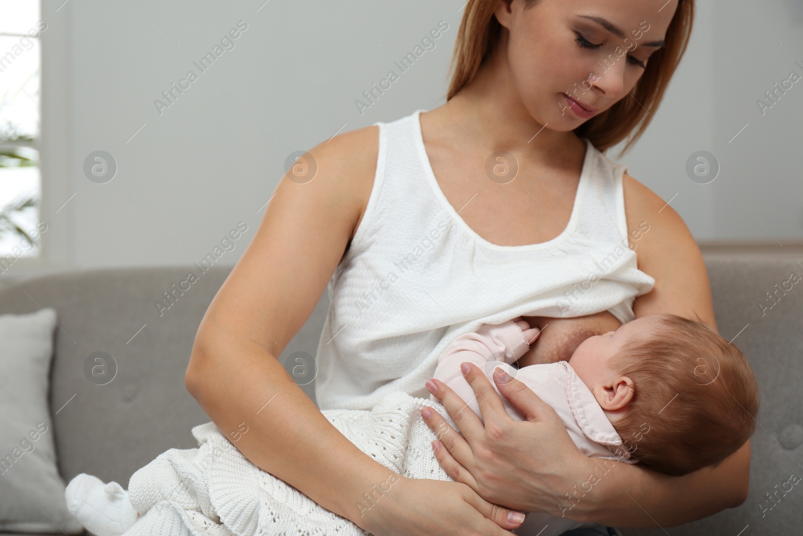 Photo of Young woman breast feeding her little baby at home