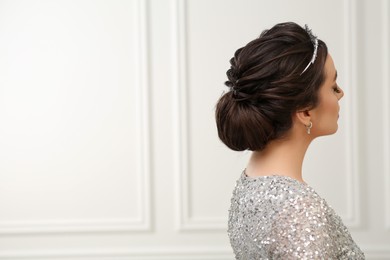 Woman with beautiful hairstyle wearing luxurious tiara indoors, space for text