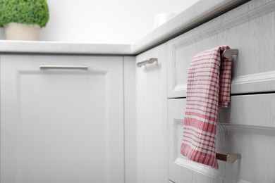 Photo of Soft kitchen towel hanging on drawer handle indoors, space for text