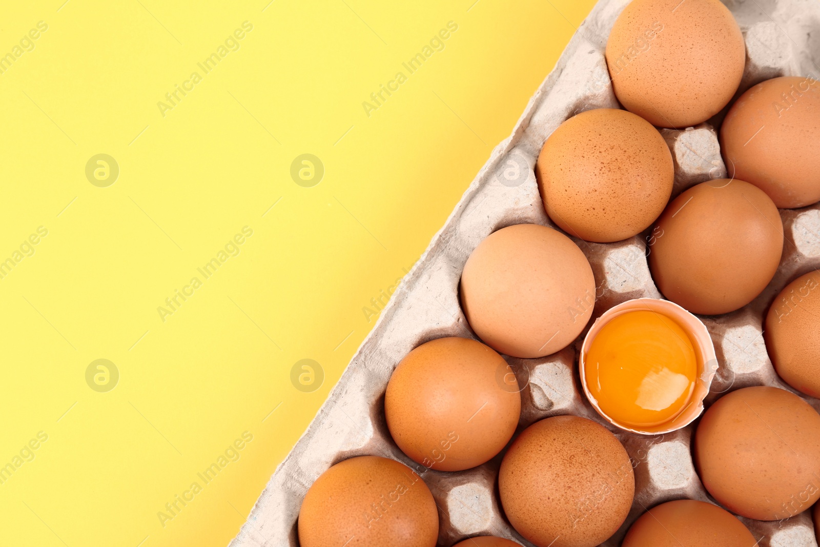 Photo of Raw chicken eggs on yellow background, top view. Space for text