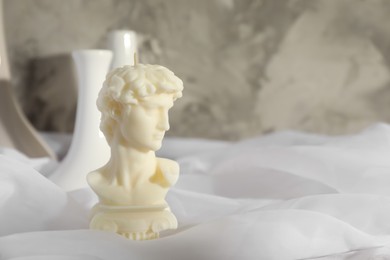 Beautiful David bust candle on white fabric. Space for text