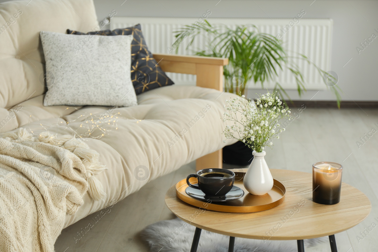 Photo of Sofa and round wooden table with decorative elements in living room. Interior design