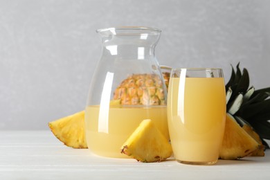 Photo of Delicious pineapple juice and fresh fruit on white wooden table