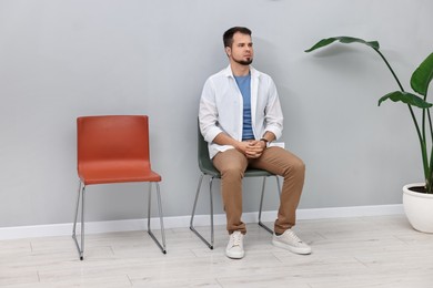 Photo of Man sitting on chair and waiting for appointment indoors