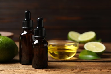 Photo of Lime essential oil and cut citrus fruits on wooden table. Space for text