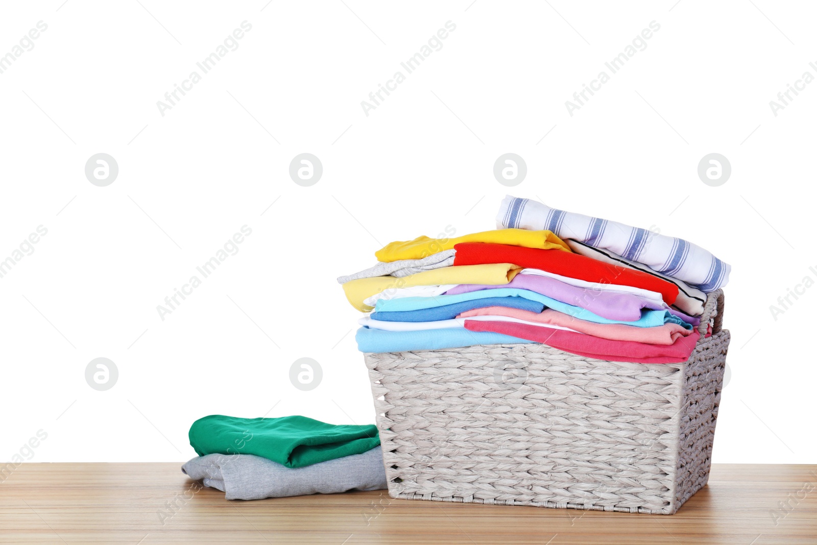 Photo of Basket with clean laundry on wooden table, white background