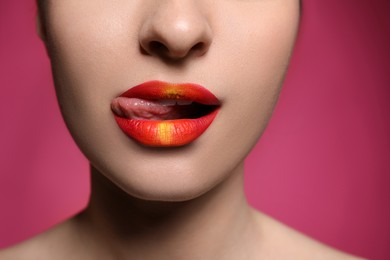 Photo of Young woman with beautiful lips makeup on pink background, closeup