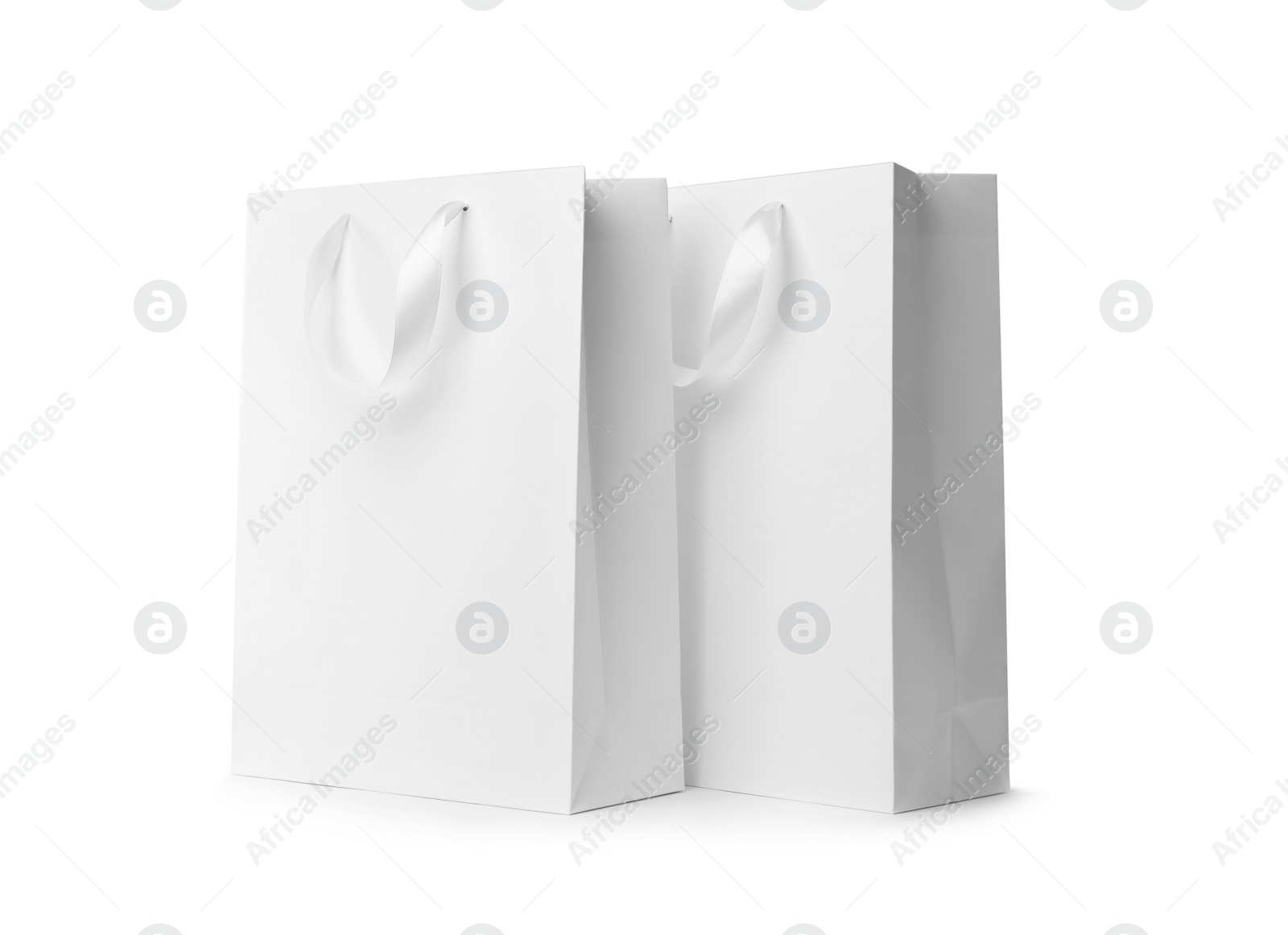 Photo of Paper shopping bags with ribbon handles on white background. Mockup for design