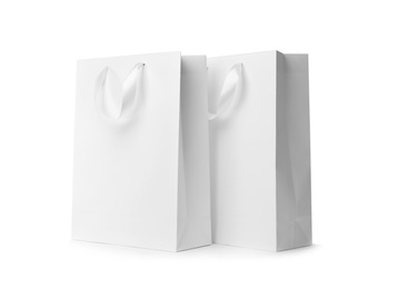 Photo of Paper shopping bags with ribbon handles on white background. Mockup for design