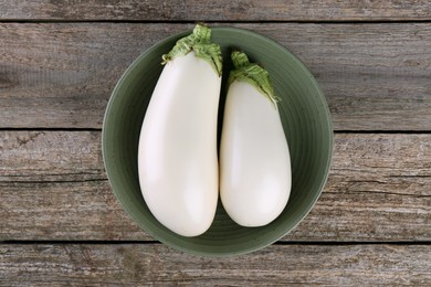 Photo of Fresh white eggplants in bowl on wooden table, top view
