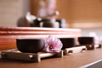 Photo of Cup with sakura flower for traditional tea ceremony on wooden table