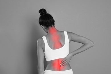 Image of Woman suffering from back pain on grey background