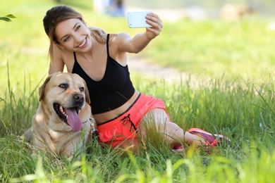 Young woman taking selfie with her dog outdoors. Pet care