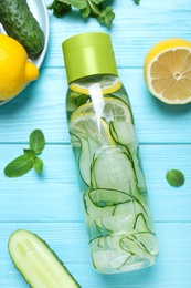 Bottle of refreshing water with cucumber, lemon and mint on light blue wooden table, flat lay