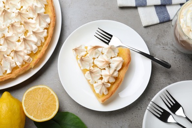 Photo of Cut delicious lemon meringue pie served on grey table, flat lay