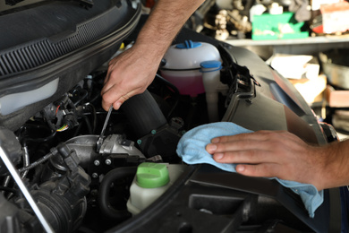 Professional auto mechanic fixing modern car in service center, closeup