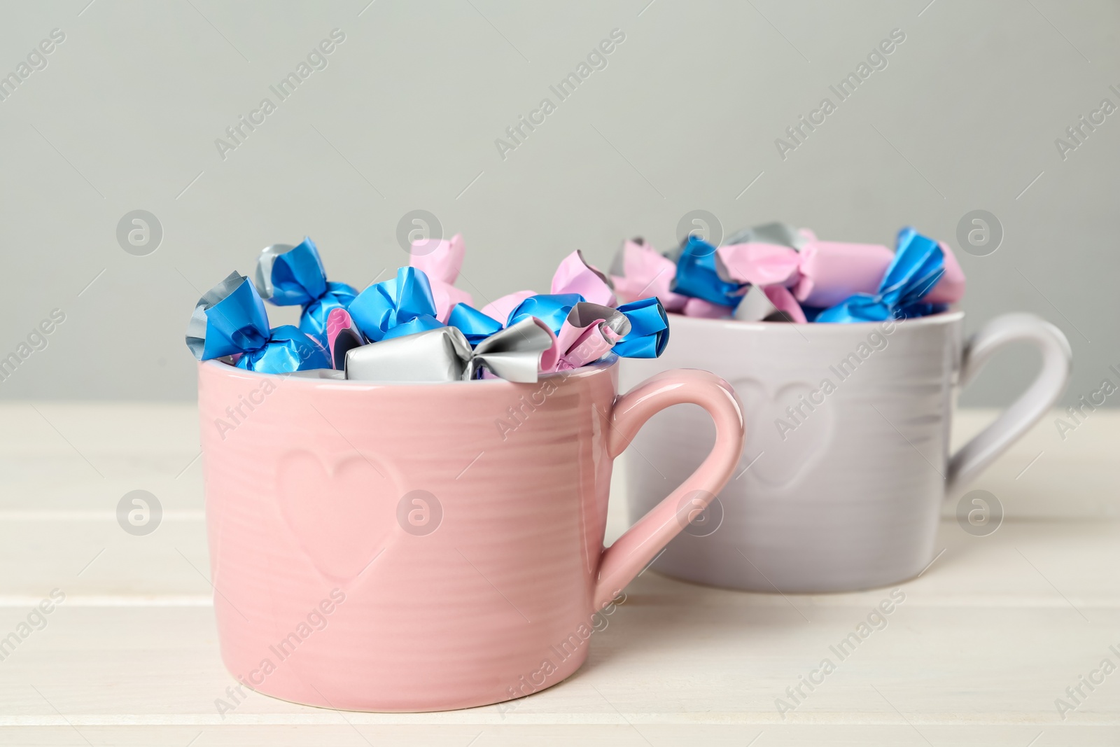 Photo of Candies in colorful wrappers on white wooden table