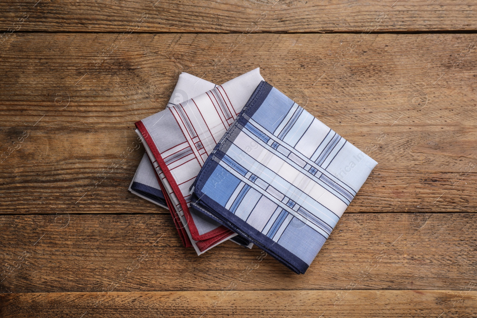 Photo of Different handkerchiefs folded on wooden table, flat lay