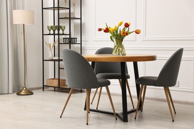 Photo of Stylish dining room interior with comfortable furniture and beautiful tulips