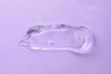 Clear cosmetic gel on violet background, top view