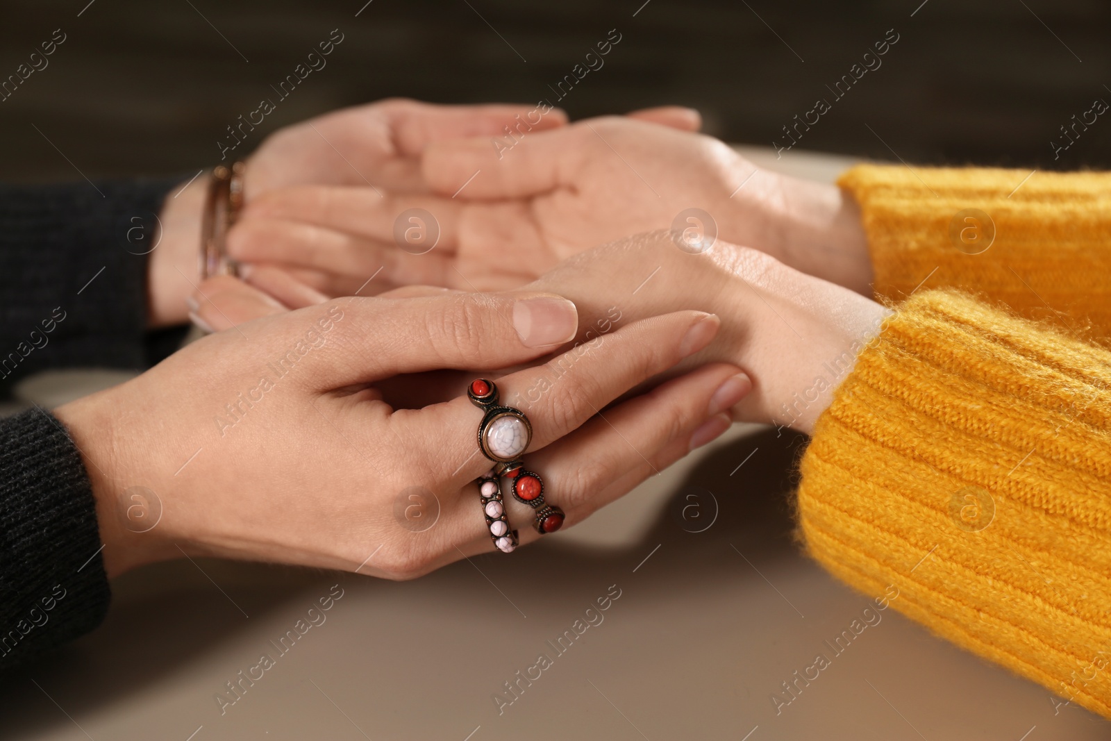 Photo of Chiromancer reading lines on woman's palm at table, closeup