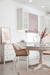 Dining room interior with tea set on round table and wicker chairs