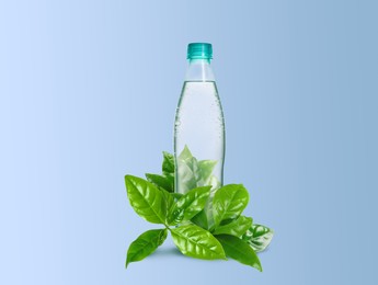Image of Bottle made of biodegradable plastic and green leaves on light blue background