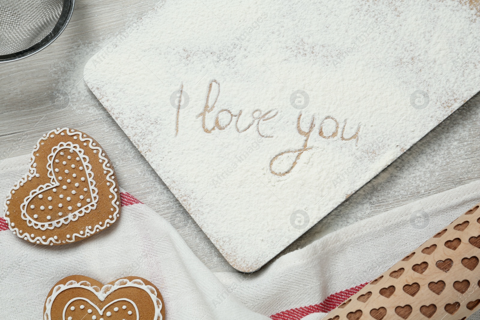 Photo of Board with phrase I Love You written in flour, flat lay composition on table