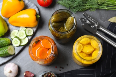 Photo of Flat lay composition with jars of pickled and fresh vegetables on grey table