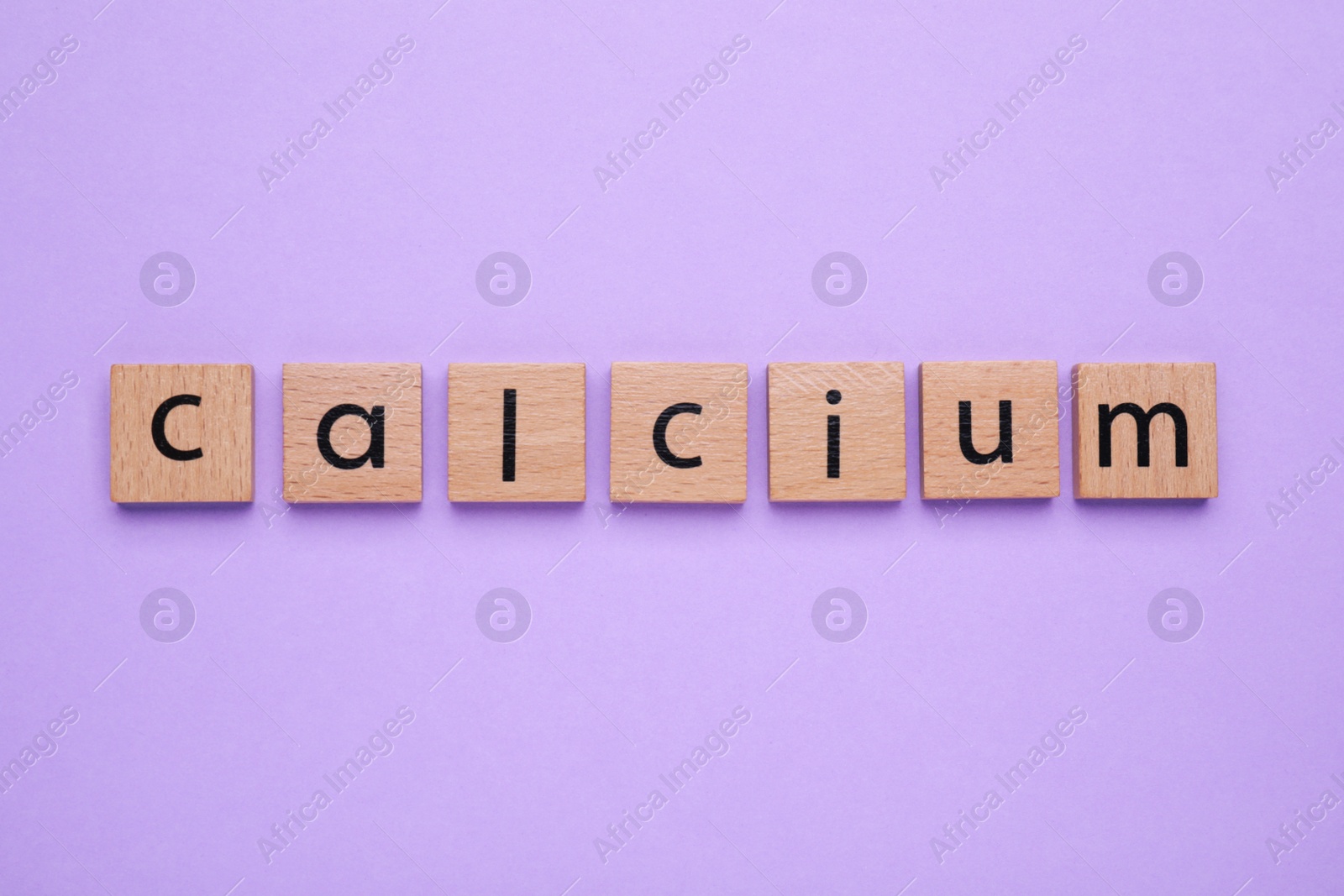 Photo of Word Calcium made of wooden cubes with letters on violet background, top view